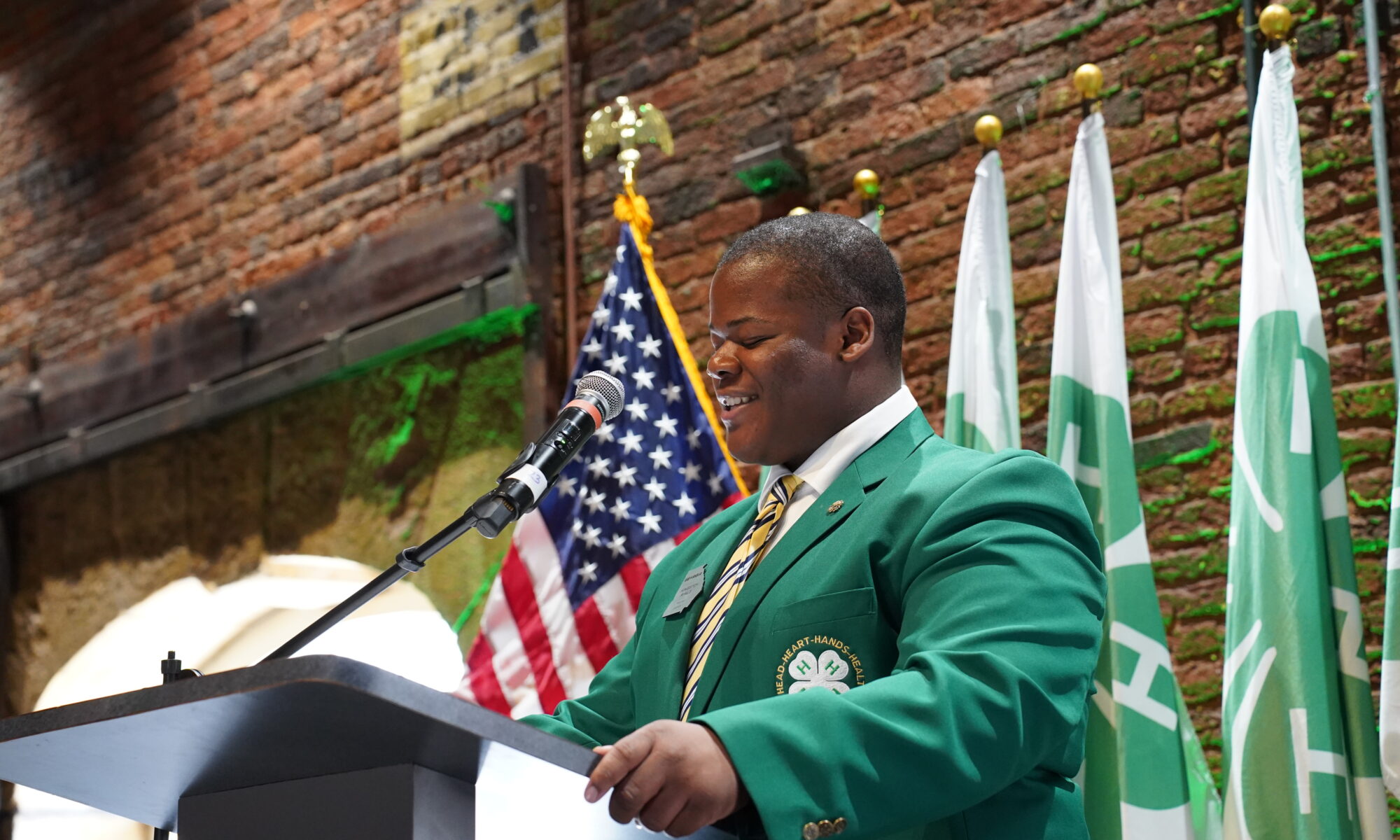 Kingston Ryals standing at a podium in front of an American flag.