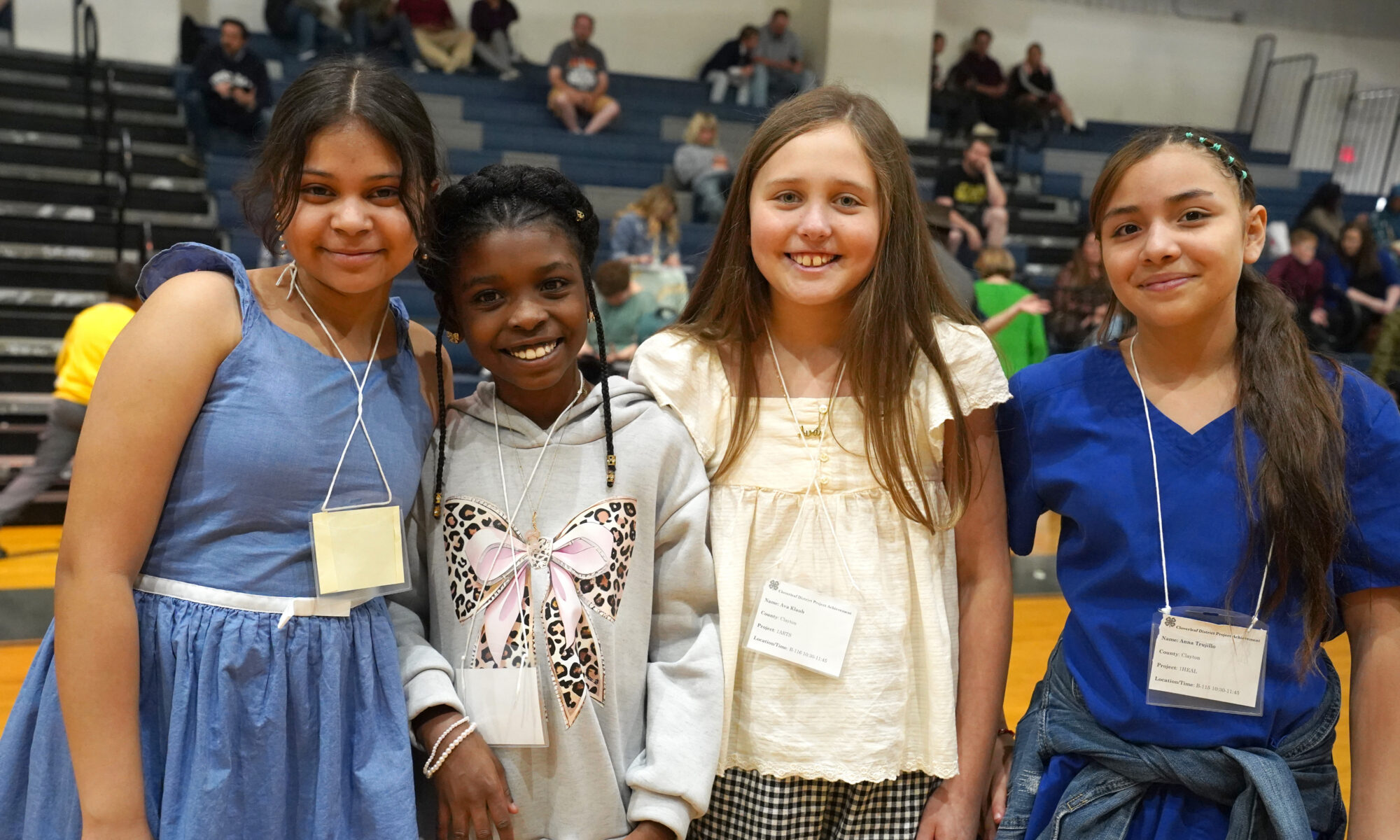 Four girls smiling at the camera in a school gym
