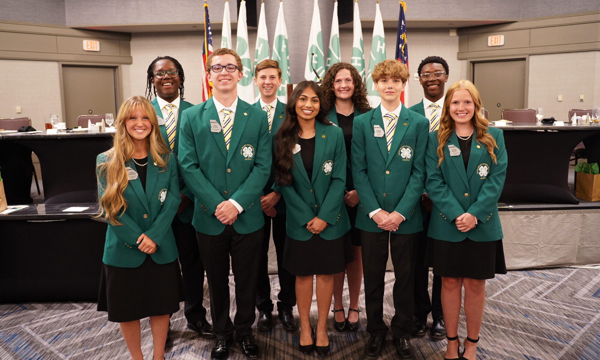 A photo of a group of nine students wearing green jackets at State Congress.