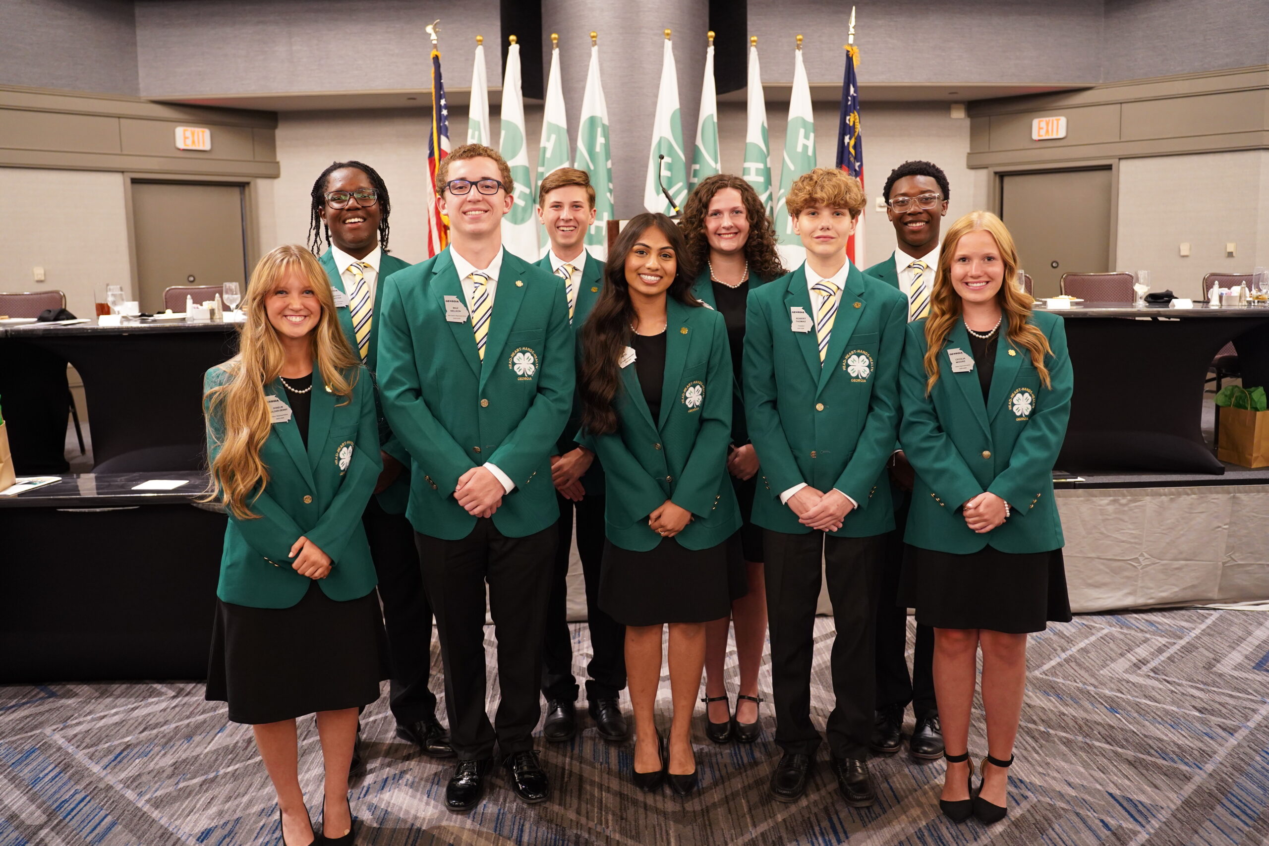 A photo of a group of nine students wearing green jackets at State Congress.