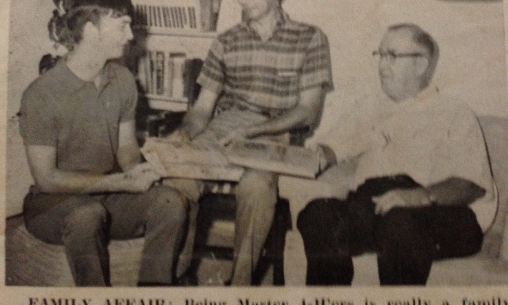 Three men sit together in a black and white newspaper clipping.